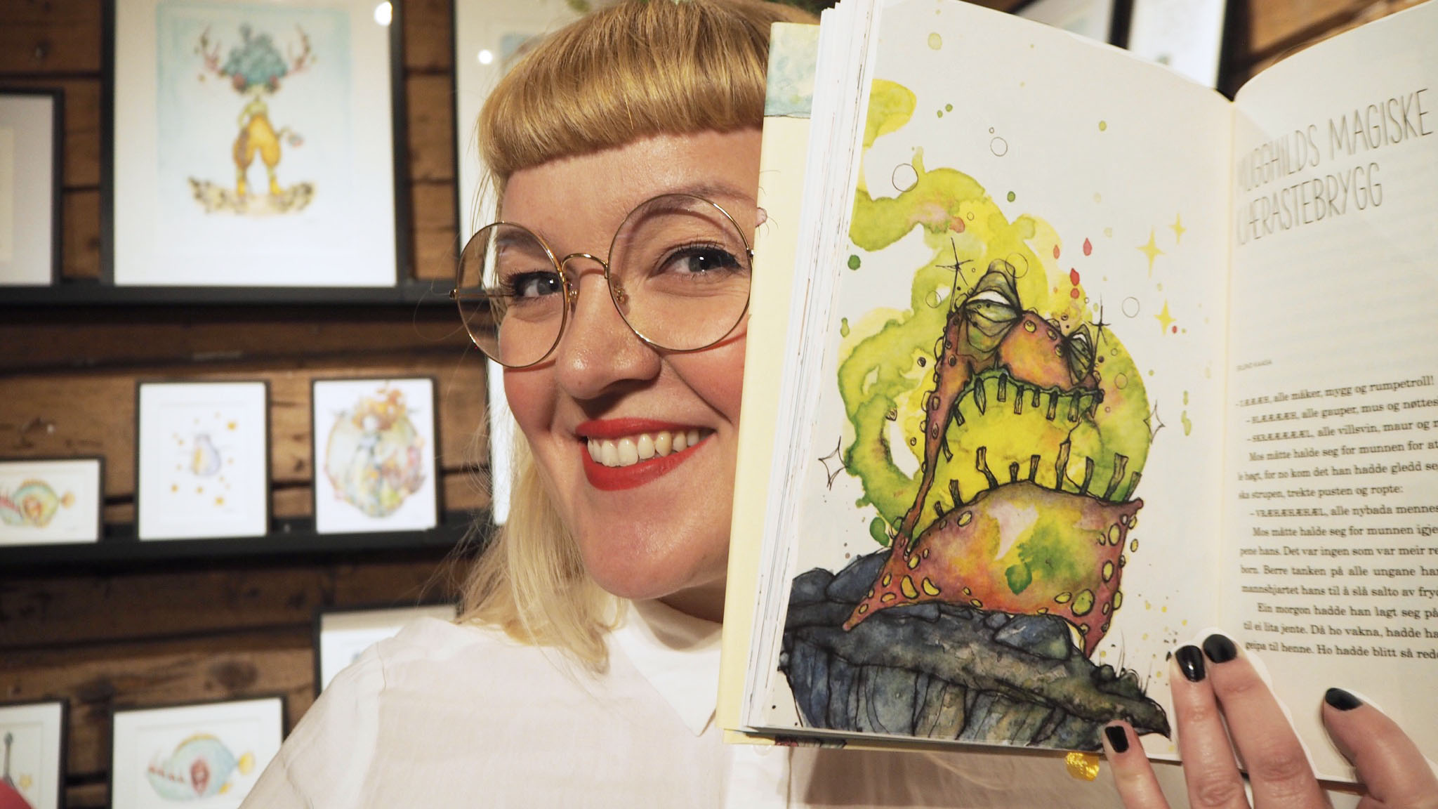 Picture of Gunvor Rasmussen holding a book with her watercolor illustrations